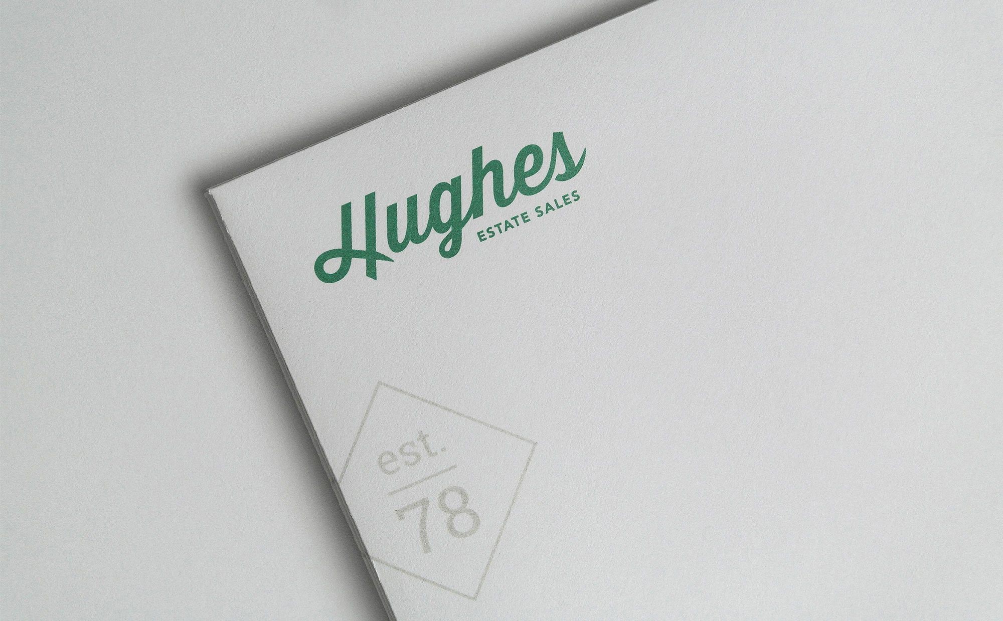 close up of hughes logo in green on antique gray paper with